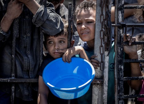 Palestinian children wait to receive hot meals in the Gaza Strip.