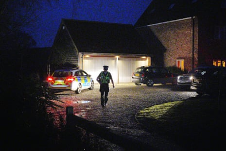 Police walking towards a house in the evening.