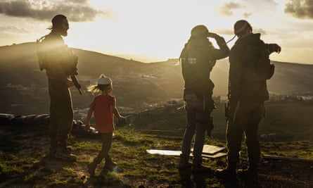 Three armed people and a young boy stand on a hillside in setting sun