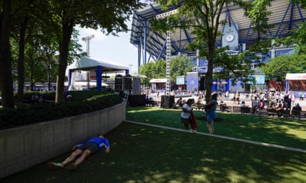 A man rests in the shade as temperatures stay high at the US Open.