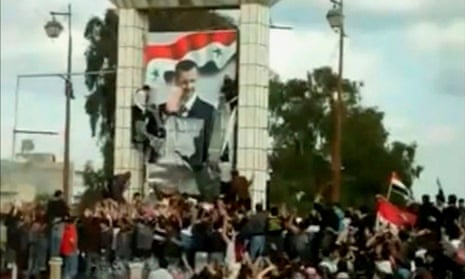 crowd around a huge poster of Assad