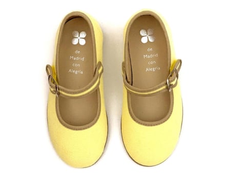 A birds eye view of a pair of Bouton d’or ballerina shoes in lemon yellow with an ochre trim, There is a single buckle strap on each show
