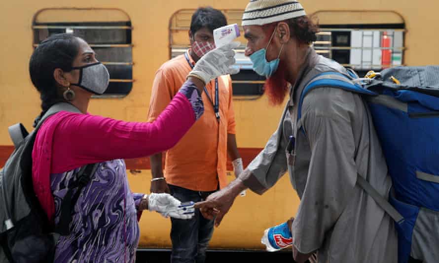 A health worker checks a passenger’s temperature and pulse at a railway station in Mumbai