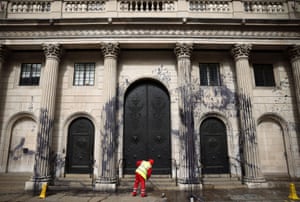 A council worker cleans the floor in front of the Bank of England building which had been sprayed with black liquid during a protest by Extinction Rebellion activists, a global environmental movement, in London.