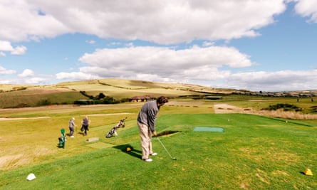 A golfer tees off on a coastal links course