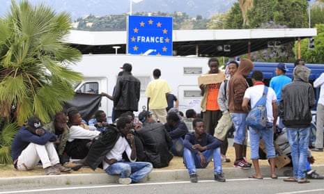Migrants wait at a border crossing between Italy and France near the city of Ventimiglia