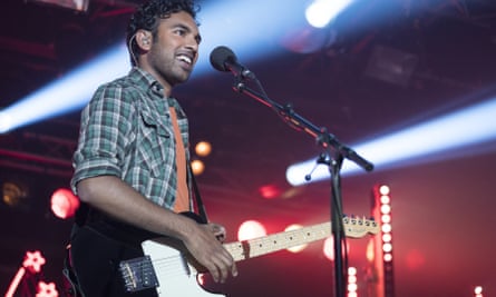 Himesh Patel on stage with a guitar in a scene from “Yesterday.”