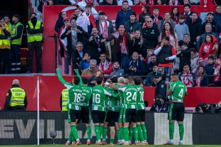 Real Betis teammates gather around Pablo Fornals by the corner flag after he scored