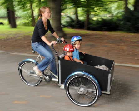 A woman driving her two children with a cargo bike.