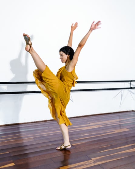A jazz dancer performing a high kick beside a barre in a studio