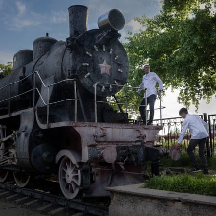 Two boys in white formal shirts play on an old steam locomotive