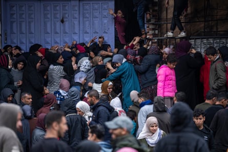 A crowd of people reach up outside a building