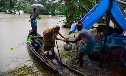 A family bring their belongings to a makeshift camp in Morigaon district of Assam