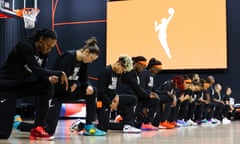 basketball players kneel before the start of a game