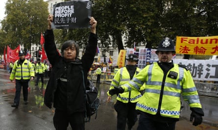 A protester is moved on by police as he takes part in a demonstration against the visit of Xi Jinping.