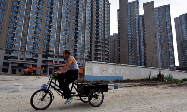 A man cycles past the construction site of a housing complex in Beijing