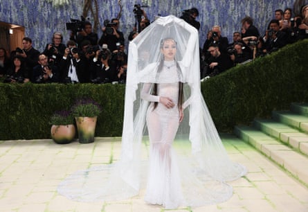 Lisa posing on red carpet with false arms holding up her veil above her head