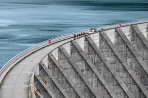 The peloton passes over a dam.