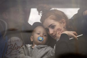A woman holds her baby inside a bus as they leave Kyiv