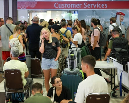Stranded passengers wait near Emirates customer service office at Bali airport after flights to Doha, Dubai, and Abu Dhabi were cancelled.