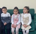a boy and two girls sit on a sofa