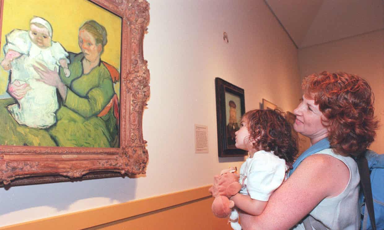 Photo of a woman standing in front of an audience pointing to a Vermeer painting