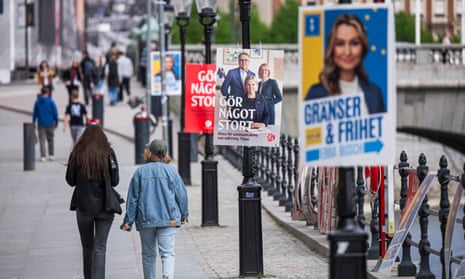 As pessoas passam por cartazes eleitorais dos sociais-democratas suecos e do partido dos democratas-cristãos antes das próximas eleições europeias em Estocolmo, em 20 de maio.