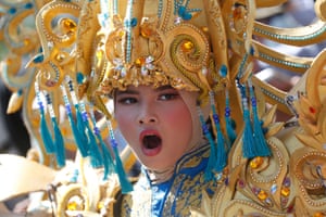 A person in a jewelled costume and headdress yawns