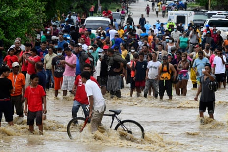 People wait for help on a flooded main roadin La Lima, Honduras