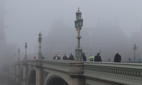 Pedestrians and morning commuters walk on Westminster Bridge shrouded in thick fog.