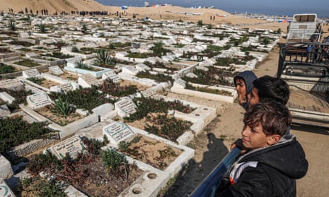 Palestinian children look on at a cemetery in Rafah,.