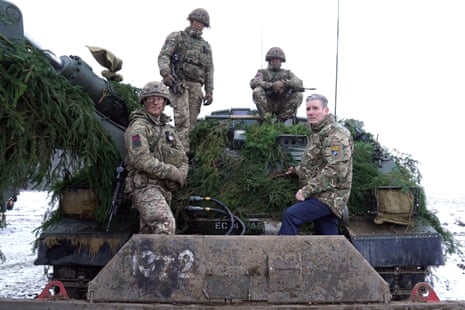 Starmer with troops on a vehicle.