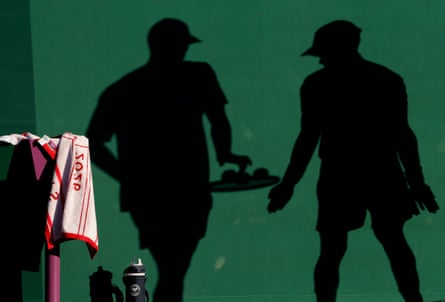 Shadows on the green wall show a ballboy give three balls to Jan Choinski