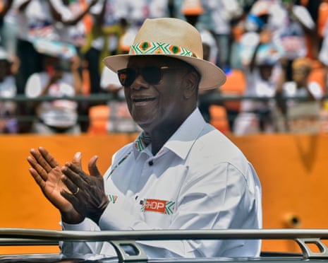 Alassane Ouattara applauds from the back of an open-top vehicle