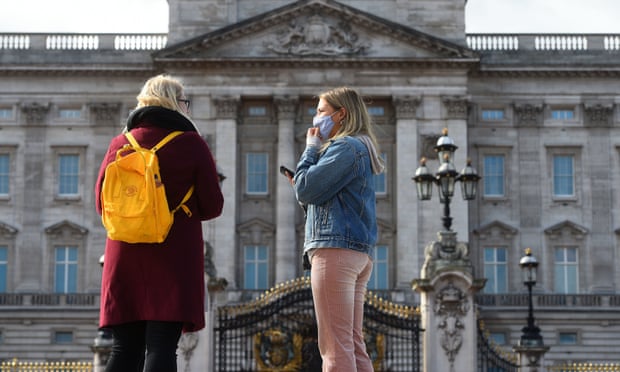 A woman wearing a mask outside Buckingham Palace in London.