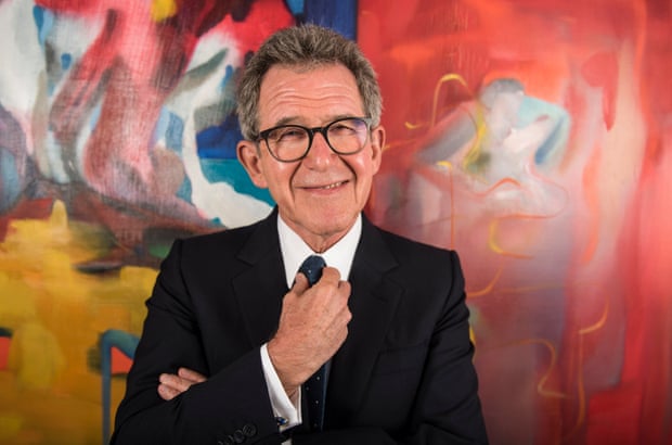 john browne in suit and tie standing in front of an abstract oil painting at his mayfair office