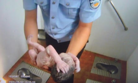Handout image shows a frame grab of a Beijing Tianqiao Police video taken on August 2, 2015 that shows a Chinese policeman holding an abandoned newborn baby in a public toilet in Beijing. 