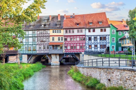 A medieval bridge with brightly coloured, timbered buidlings on it and a river flowing underneath