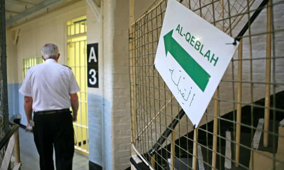 A guard walks past a sign to the mosque inside Wandsworth prison. 