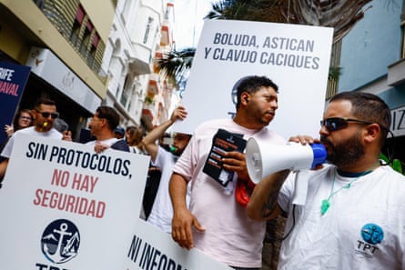 A protesters with a megaphone with others carrying banners