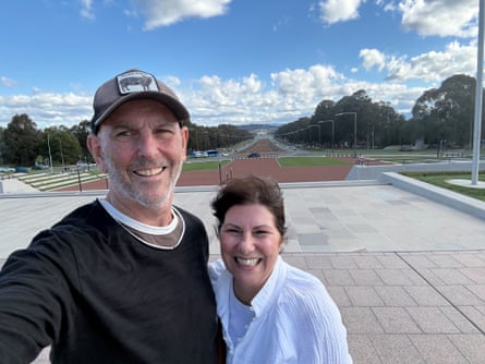 Kev and Danielle Smith smile for a selfie overlooking a tree-lined boulevard in Canberra