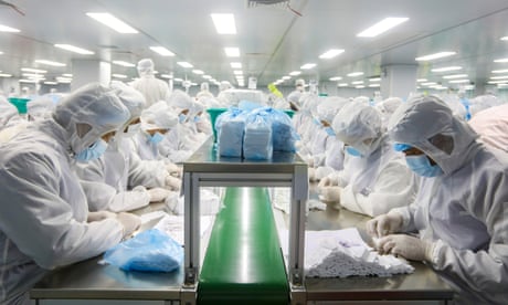 Employees in full protective gear work on the Covid antigen rapid test kits in a Shenzhen laboratory