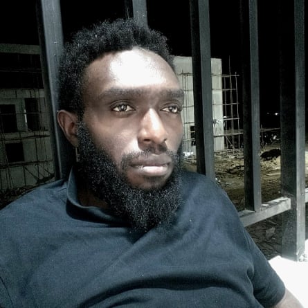 A man’s head and shoulders. Railings can be seen behind him