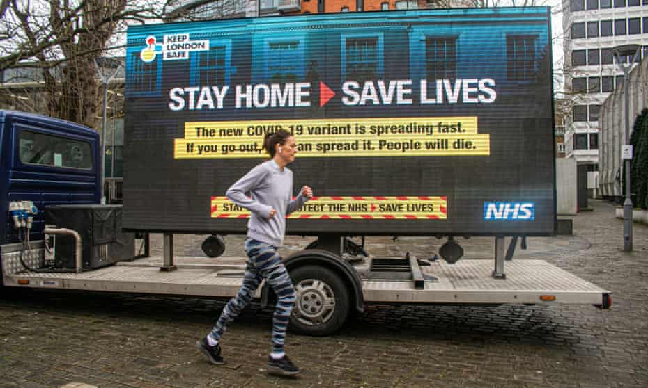 A jogger in London runs past an NHS Covid sign on Thursday