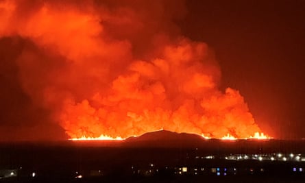 The volcano spews lava and smoke as it erupts, as seen from the town of Keflavik.