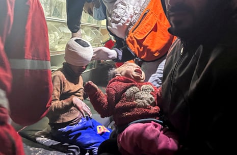 A young boy and baby girl are treated by medical staff after being freed from a destroyed house