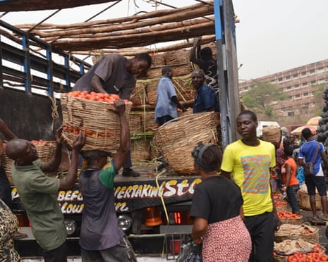 Workers unload tomatoes at a market in Enugu, Nigeria