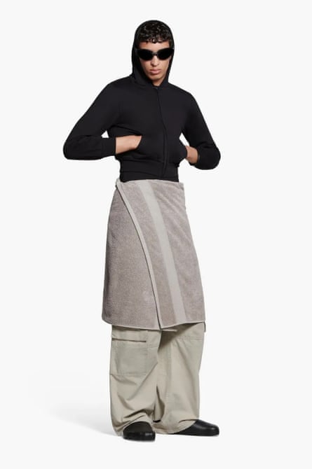 Man wears black hoodie over grey towel skirt, which looks just like a bath towel