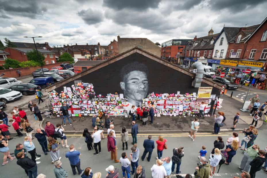 People look at the messages of support and the newly repaired mural of England footballer Marcus Rashford by the artist known as AKSE_P19, which is displayed on the wall of a cafe on Copson Street, Withington, after AKSE_P19 came to repair it today after it was defaced by vandals in the aftermath of England’s Euro final loss on July 13