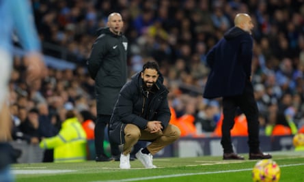 Ruben Amorim kneels on the touchline during the game.